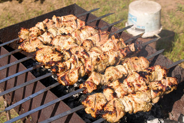 Kebab grilling on metal skewers. Meat on the grill. Close up.