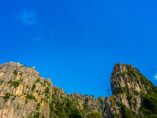 Stone cliff mountain with green forest on Blue sky background.