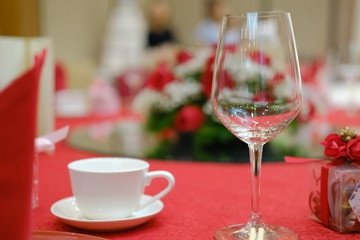 A cup and a glass on a red table