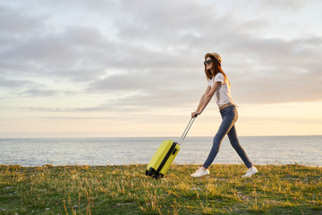 young woman with suitcase on country road
