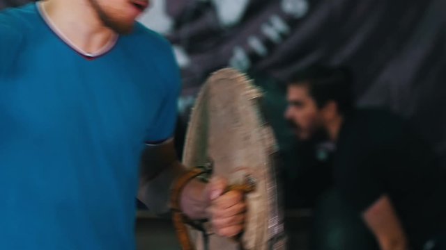 Knights training - a man training his sword fighting skills on the bunch of tires holding a wooden shield