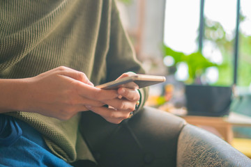 People hand using smartphone with blur cafe shop background.