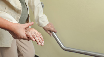 Elderly woman holding on handrail with caregiver - obrazy, fototapety, plakaty