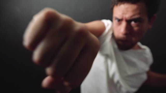 man with white shirt fighting in a black background