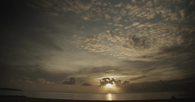 Amazing sunset behind an epic cloudscape with waves crashing on a beach
