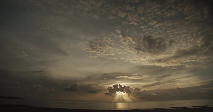 Sun sets on the coastline with an epic cloudscape and sun rays visibly shining through