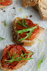 Delicious homemade bruschetta with whole grain bread, grilled tomatoes and fresh arugula. Vegetarian healthy snack, vegan food