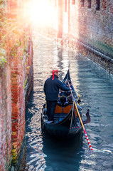 Obraz premium Venetian gondolier punting gondola through green canal waters of Venice Italy