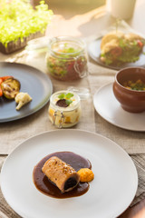 Different tasty dishes on the restaurant table, meat roll on the plate