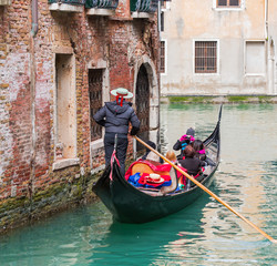 Fototapeta na wymiar Venetian gondolier punting gondola through green canal waters of Venice Italy