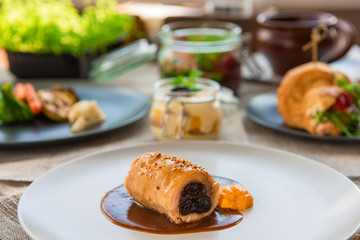 Different tasty dishes on the restaurant table, meat roll on the plate