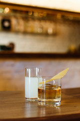A cocktail in rocks glass and a cocktail in highball glass on the bar counter. Warm lifestyle image, selective focus, natural light