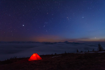 Fairytale landscapes of the winter Carpathian Mountains with a charming milky way in the sky tourist tents and snowy houses in the valleys	