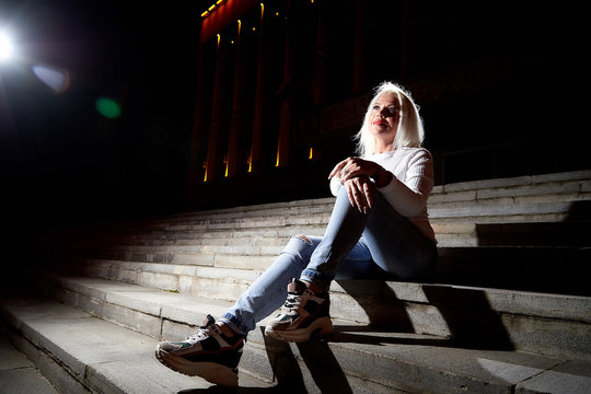 Fototapeta Ugly woman on the steps of stair in the city at night with lighting flashes in the black background