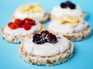 Crispbread with cottage cheese, blackberries and other fruits on a blue background
