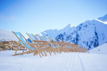 Sun loungers against backdrop of mountains at winter resort