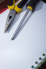 Screwdriver and pliers on a notebook