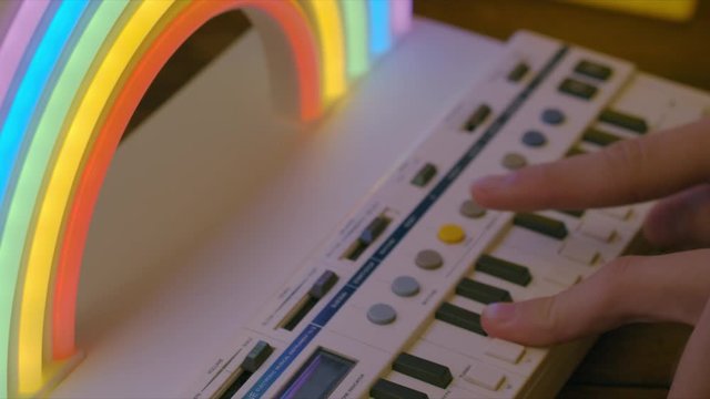 Kids hands playing keyboard with rainbow light