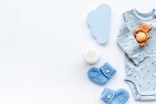 Newborn baby boy set - blue clothes as bodysuit, booties, toys - on white table top-down frame copy space