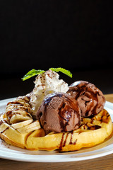 Waffle topped with chocolate ice cream , banana and wipe cream