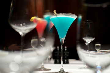 Blue cocktail in selective focus over the other glasses for abstract mood