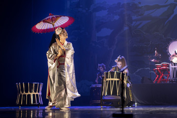 Traditional Japanese performance. Actress in traditional kimono on the dark stage with umbrella and...