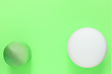 Cosmetic jars on a green background close up. Top view, copy space