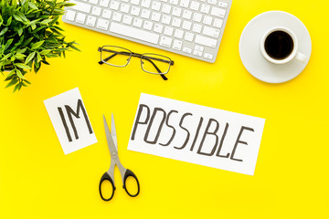 All is possible concept. Cut word impossible near scissors on yellow office background