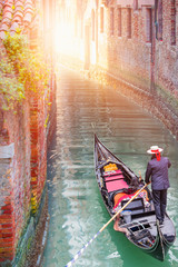 Venetian gondolier punting gondola through green canal waters of Venice Italy © muratart