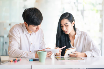 Young Asian business or college student using digital tablet and laptop computer notebook work together at coffee shop or university campus.