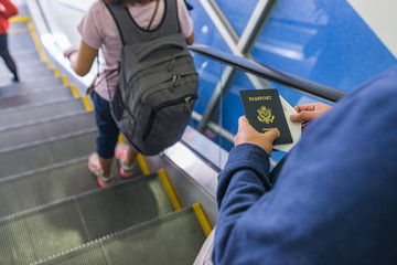 Young traveler hand holding passport standing at escalator in airport