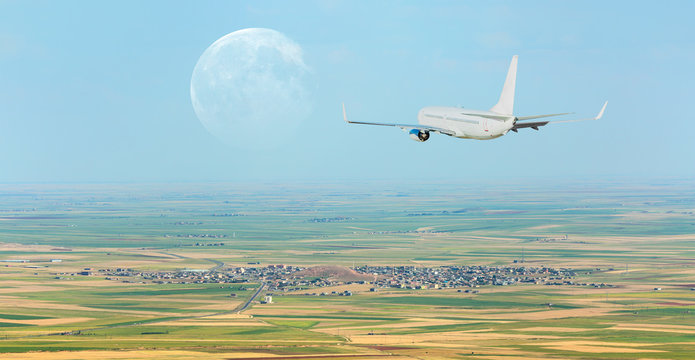 Passenger airplane flying above city with full moon "Elements of this image furnished by NASA"