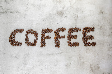 Light textured background image with coffee word written with coffee beans