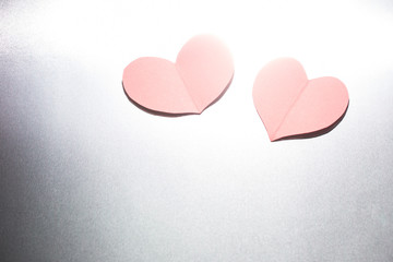 Fototapeta premium Red heart made of paper on which a shadow falls in the hand of a young man on a black background.