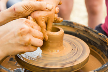 A close up view on ceramic production process on potter's wheel with children. Clay crafts with kids concept.