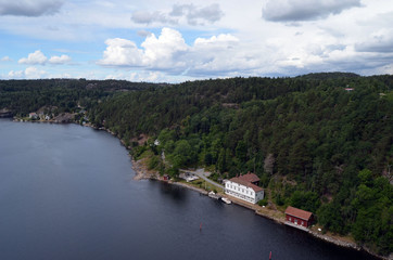 Fototapeta na wymiar Typical Swedish nature and houses on the shore of the fjord. View from the high bridge over the fjord. The border of Norway and Sweden.Near the town Selater,Sweden