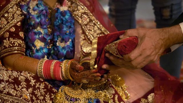 Stock video of an Indian bride performing Hindu wedding ritual at her wedding. 12 seconds of 4K stock video - Hindu wedding ritual performed by bride and family member at an Indian wedding