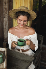 Happy woman sitting on the summer terrace and drinking coffee