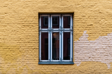 Old window on yellow painted brick wall in Lubeck