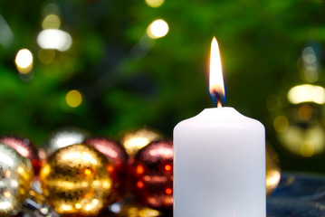 Burning candles and christmas decorations. Green balls for Christmas tree and fir twig on wooden...