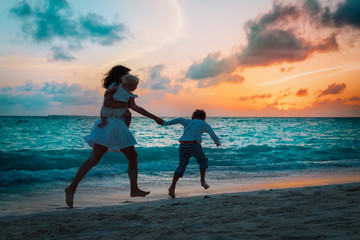 Fototapeta premium mother with kids run and play on beach at sunset