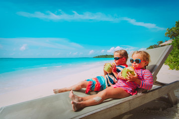 little boy and girl drinking coconut on beach