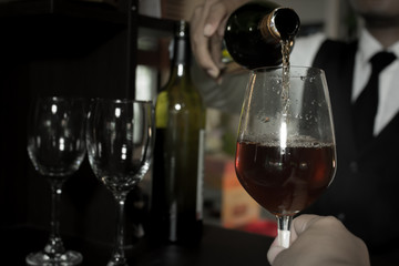 Waiter pouring wine into glasses at the bar.