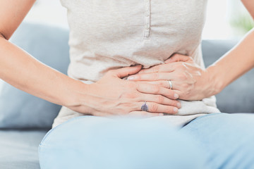 Woman with  stomach issues / problems while lying on the couch.
