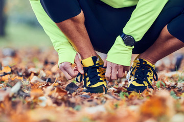 Preparing for jogging in autumn colored park.