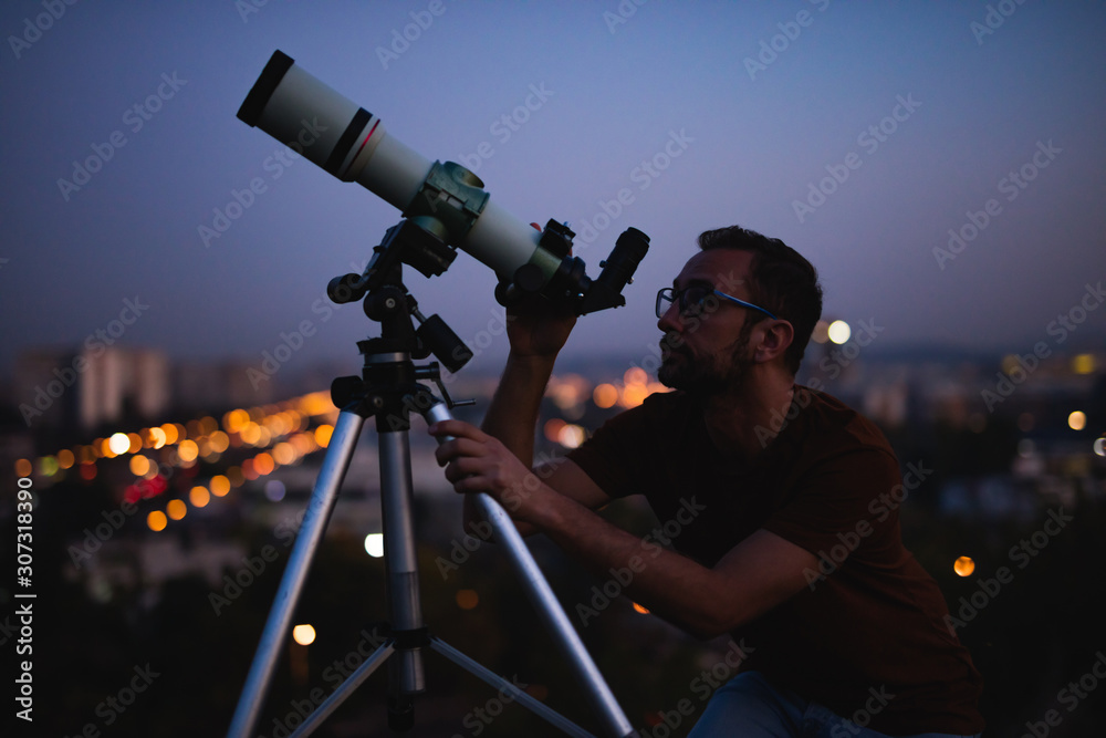 Canvas Prints astronomer with a telescope watching at the stars and moon with blurred city lights in the backgroun