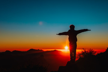 Silhouettes of happy boy enjoy travel at sunset mountains