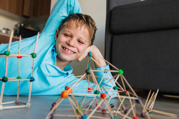 happy boy making geometric shapes from sticks and clay, engineering and STEM