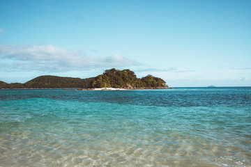 Fototapeta premium Island in the middle of blue ocean in El Nido Palawan , Philippines view from empty white sand beach , wide angle shot .