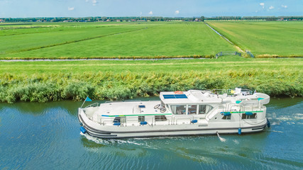 Aerial drone view of houseboat in canal and country landscape of Holland from above, family travel by barge boat and vacation in Netherlands